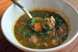Bowl of Pumpkin and Sausage Soup with Sweet Potatoes and Spinach